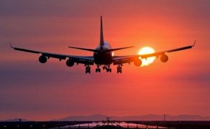 Aeroplane landing at sunset. Boeing 747 landing at sunset at Vancouver International Airport, British Columbia, Canada. The aircraft is partially obscuring the setting Sun. The landing gear is down and the angled wing tips are clearly seen. Landing lights, used to guide aircraft to the runway, are in the shadows at bottom. The aircraft flies along the line formed by these lights as it approaches the runway.