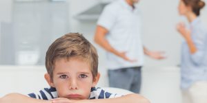 Sad boy with arms folded while parents quarreling